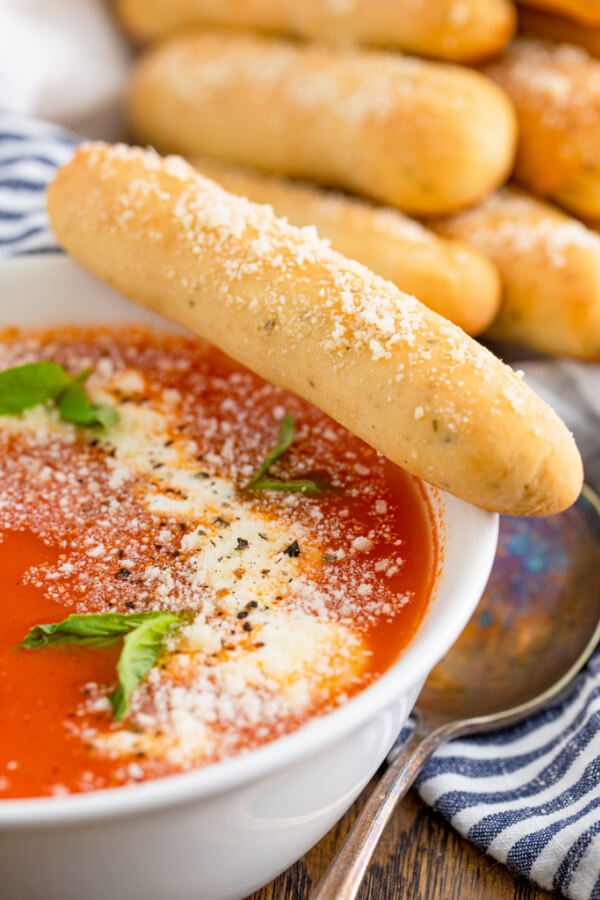 bowl of marinara sauce with a breadstick on the side
