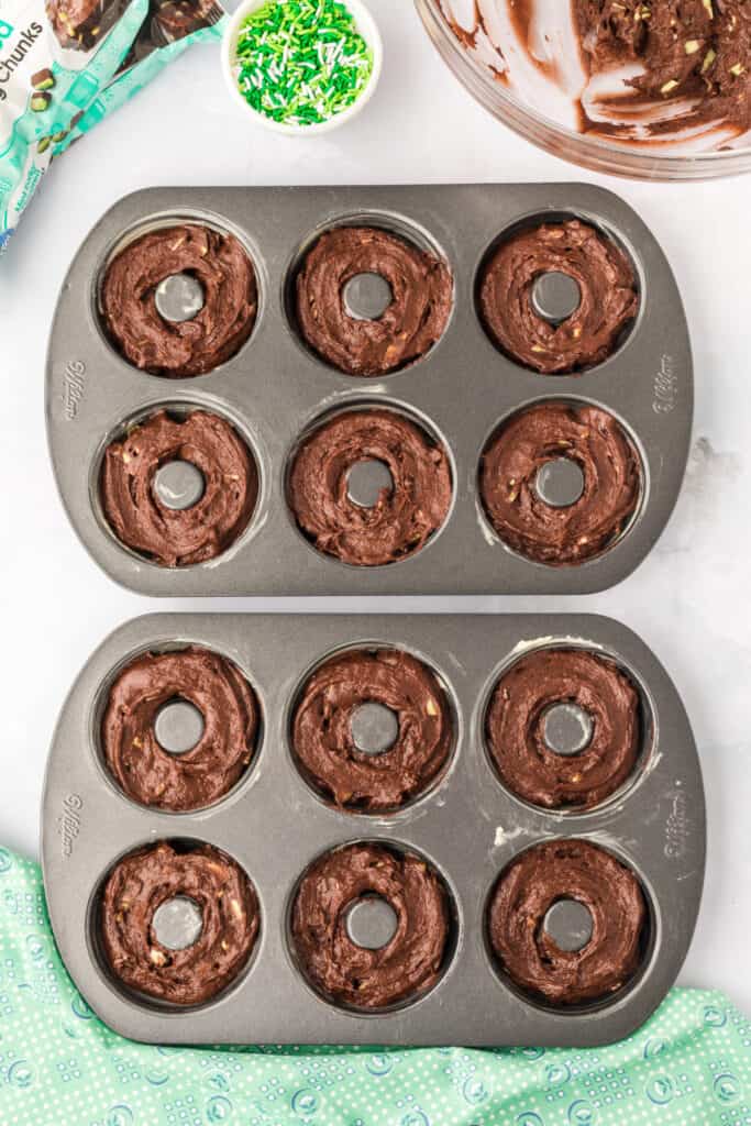 Chocolate Mint Donut batter piped into prepared donut pans before baking