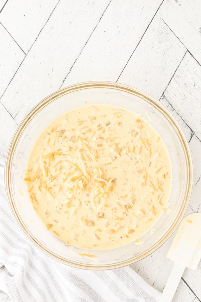 Mixed egg, cheese, and green chili casserole mixture in a glass bowl