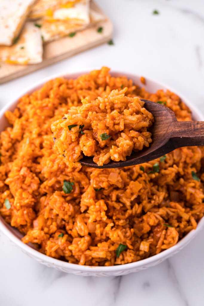 wooden spoon scooping mexican rice out of serving bowl