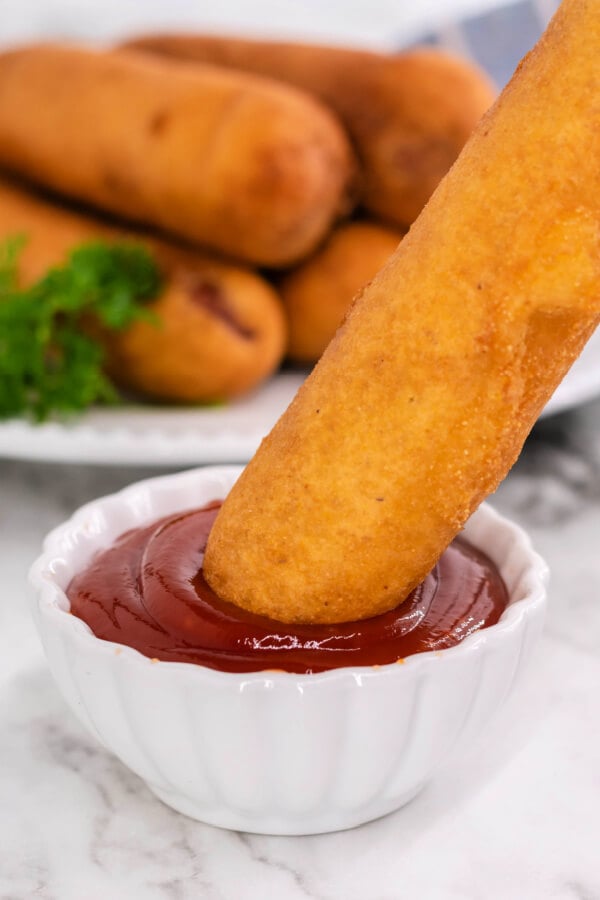 dipping a corn dog into ketchup