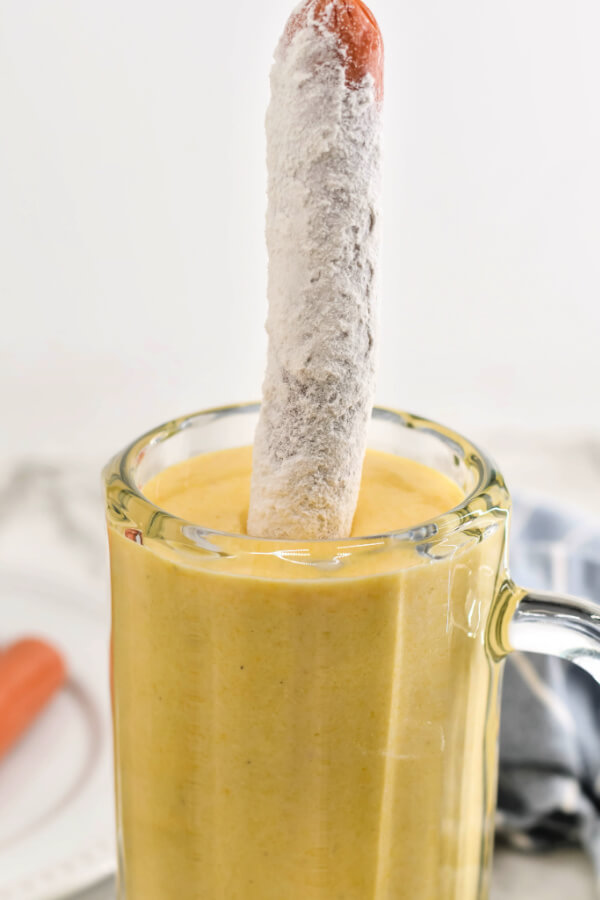 dipping the hot dog into the cornmeal batter