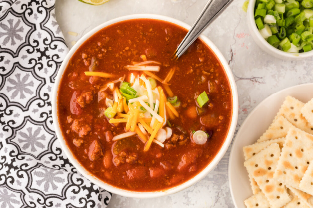 looking down into a bowl of chili garnished with cheese and green onions