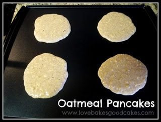 Four pancakes cooking on a griddle.