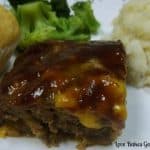 bbq bacon cheeseburger meatloaf on white plate with mashed potatoes and broccoli
