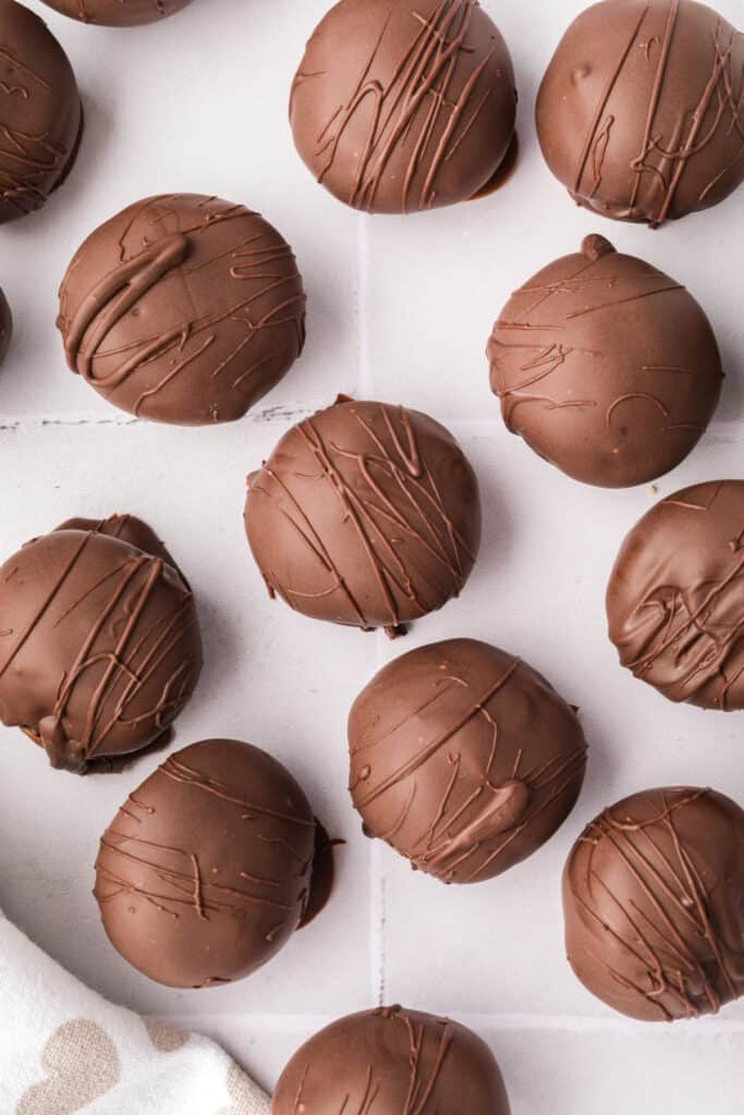 Close-up overhead shot of chocolate-dipped cookie dough truffles with chocolate drizzle detail.