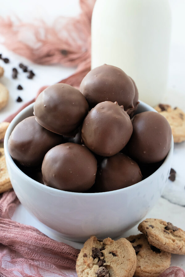 cookie dough truffles in bowl with a bottle of milk behind it