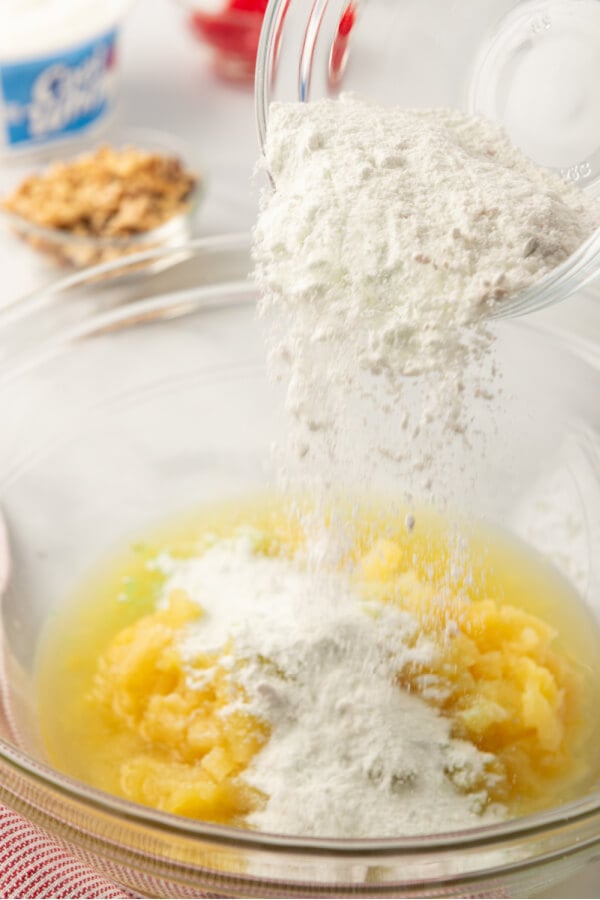 pudding mix being poured into crushed pineapple in bowl