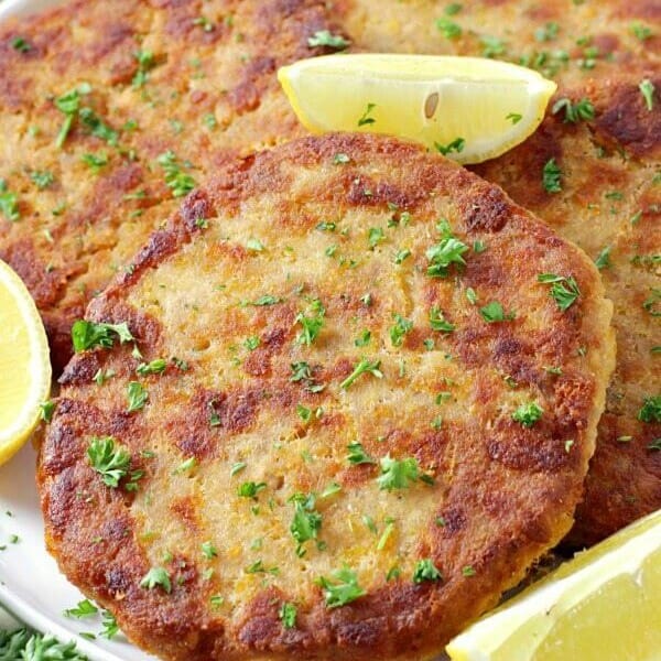 several salmon parries on a white serving platter with lemon wedges