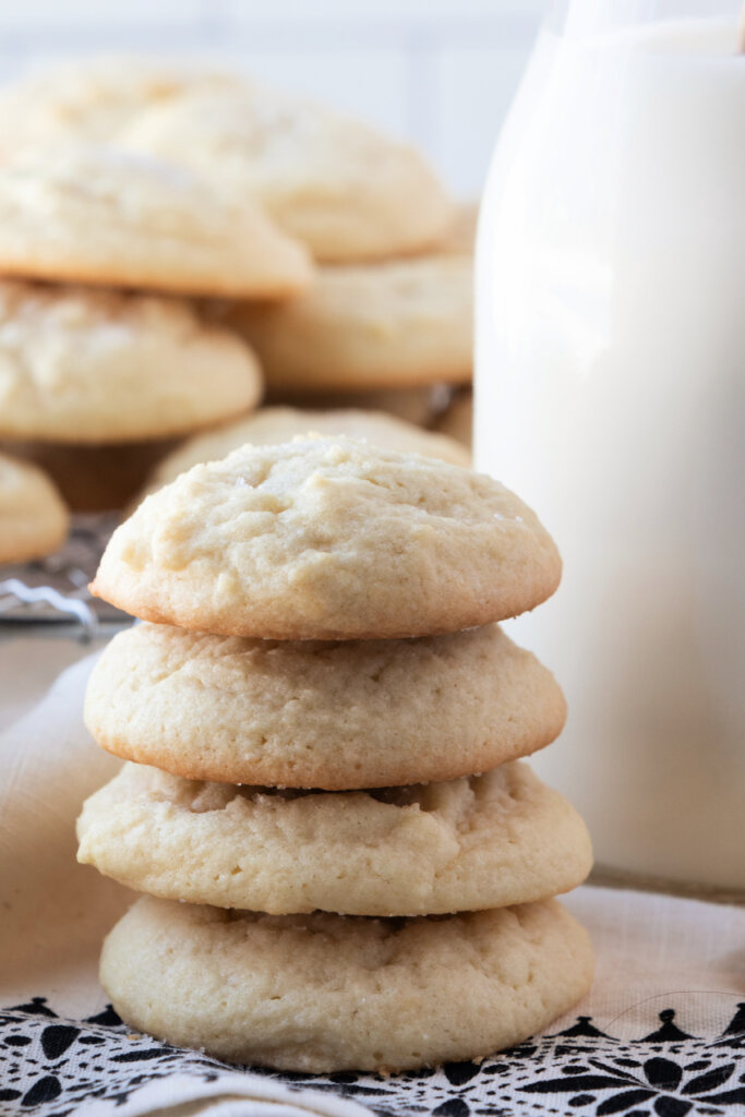 four tea cake cookies stacked next to a glass milk bottle