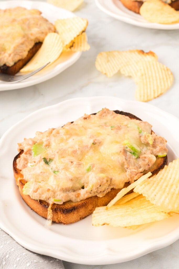 cheesy tuna melts on plates with potato chips