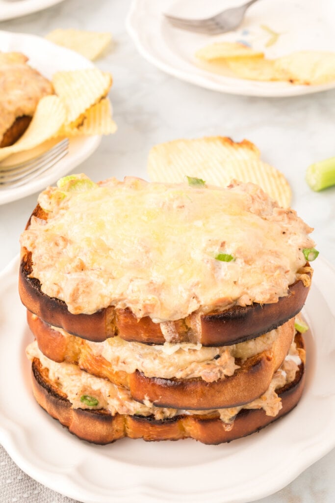 three cheesy tuna melts stacked on plate