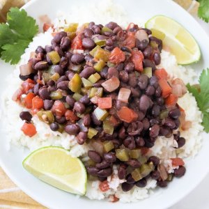 cuban black beans and rice on white plate with lime wedges