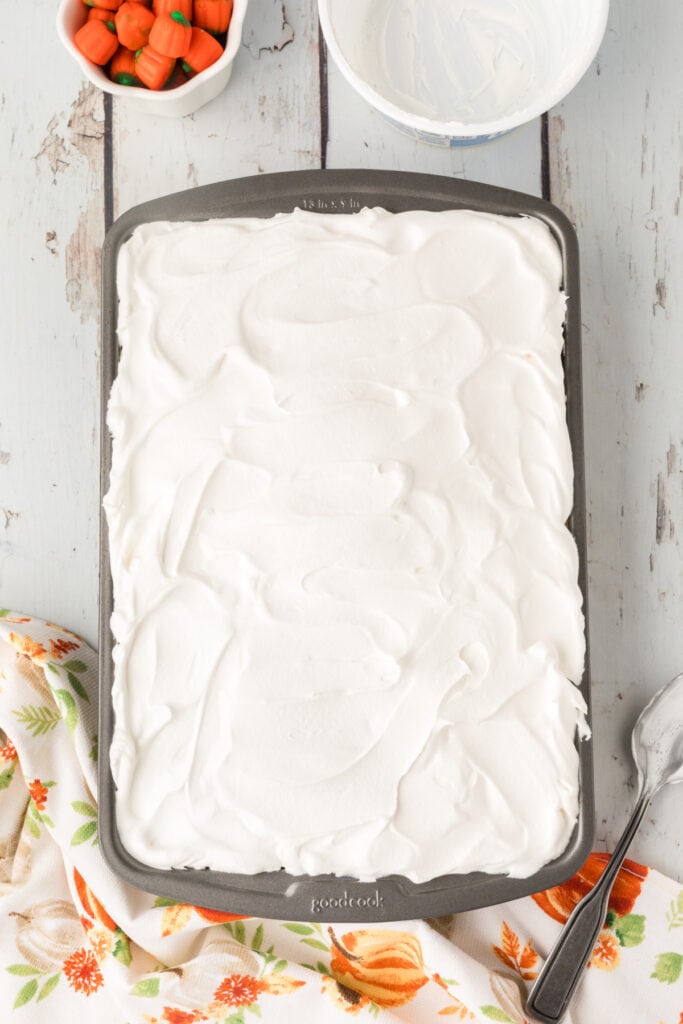 Overhead shot of cake topped with a thick layer of whipped topping in a pan