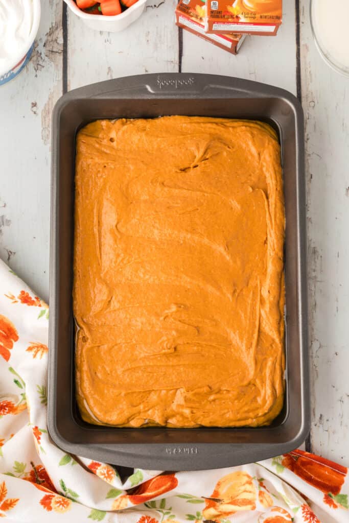Unbaked pumpkin cake batter spread in a greased 9x13 baking pan
