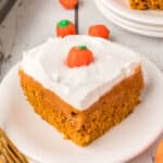 Square close-up of a slice of pumpkin poke cake with whipped topping