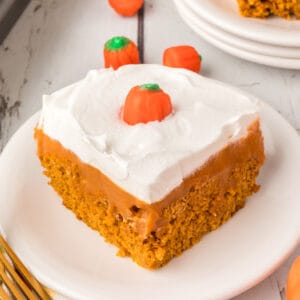 Square close-up of a slice of pumpkin poke cake with whipped topping