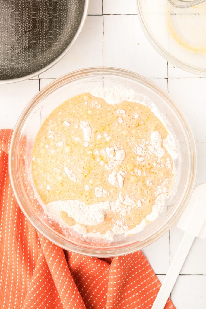 Mixing bowl with wet ingredients poured over dry mixture for pumpkin pancake batter