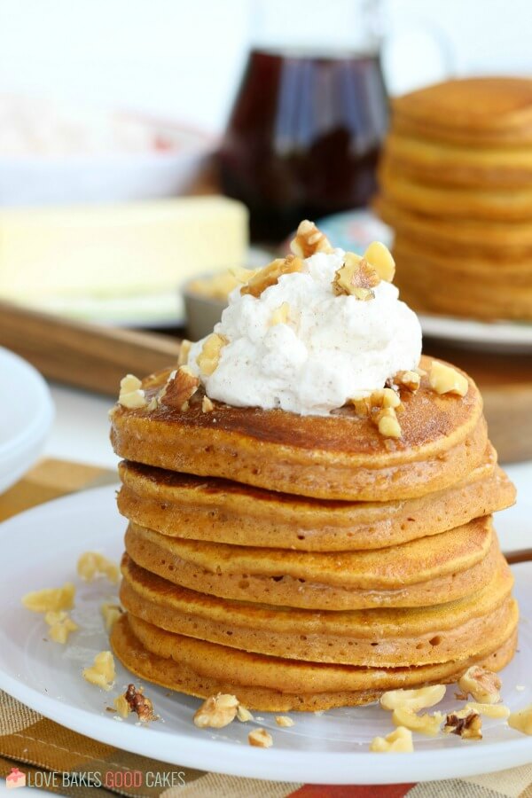 Pumpkin Pancakes are the ultimate fall breakfast. Sweet and fluffy with fresh whipped cream - perfect for chilly fall mornings! Pumpkin Pancakes stacked on a plate, the ultimate fall breakfast.