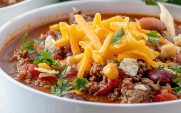 Taco Soup is a hearty and satisfying recipe with plenty of ground beef, beans, corn, and tomatoes in a zesty taco flavored broth. closeup of taco soup in bowl