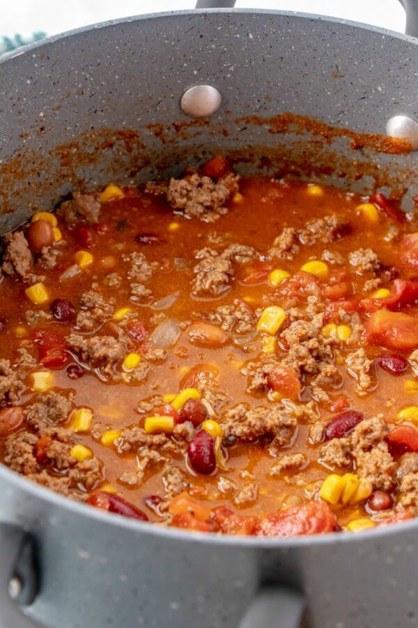 Taco Soup is a hearty and satisfying recipe with plenty of ground beef, beans, corn, and tomatoes in a zesty taco flavored broth. soup in pot cooking
