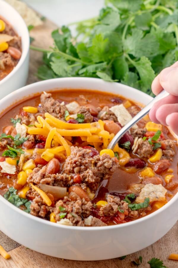 Taco Soup is a hearty and satisfying recipe with plenty of ground beef, beans, corn, and tomatoes in a zesty taco flavored broth. getting a spoonful of Taco Soup