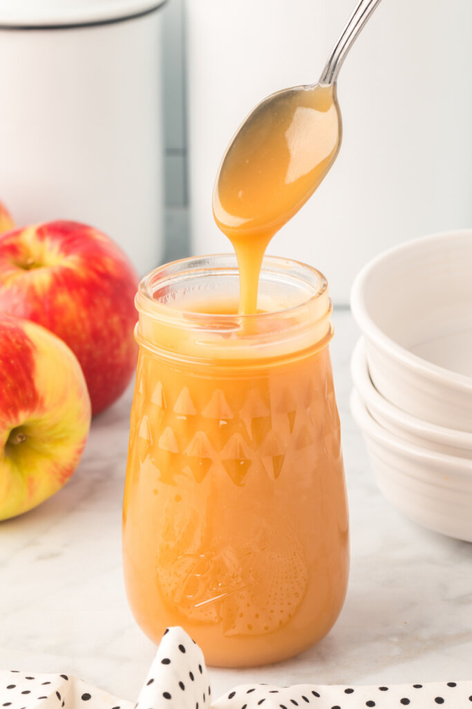 homemade caramel sauce on a spoon and in a jar