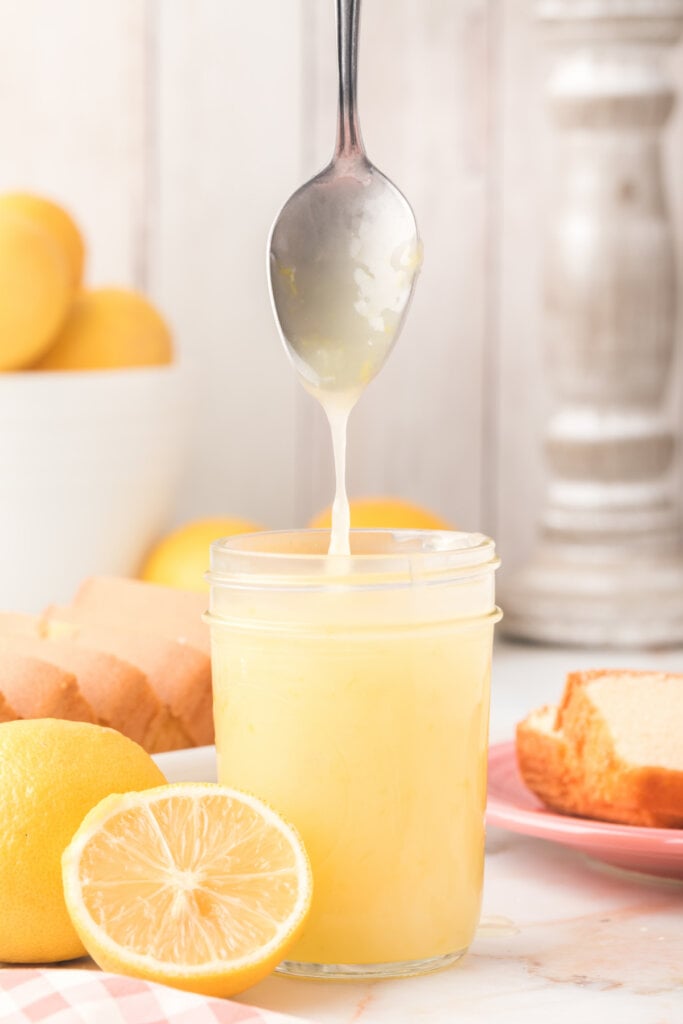 lemon sauce dripping from spoon over a glass jar