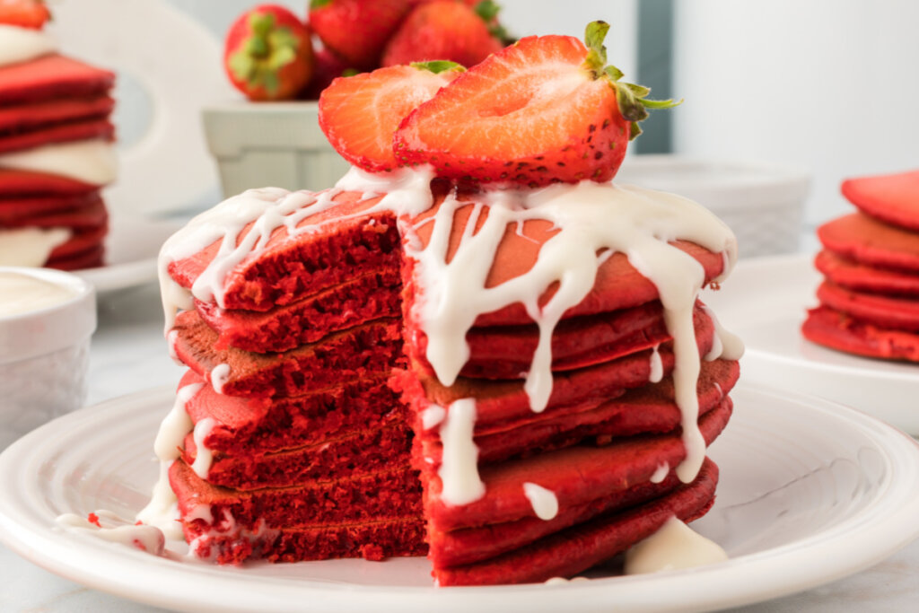 stack of red velvet pancakes with cut strawberry on top