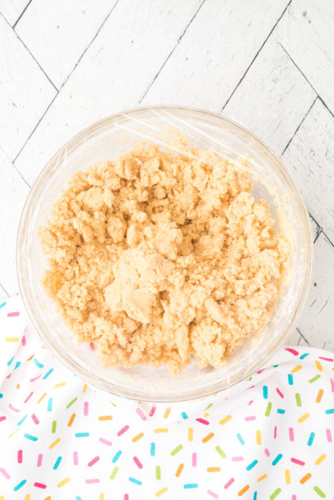 Finished cookie dough in a bowl covered with plastic wrap, ready to chill.