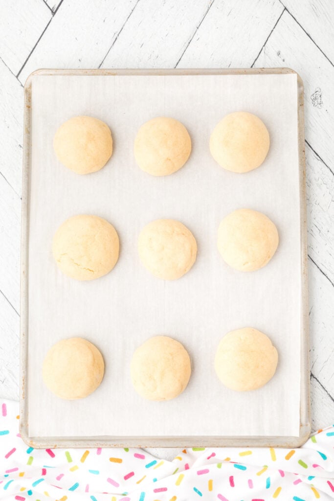 Soft sugar cookies freshly baked on a parchment-lined baking sheet.