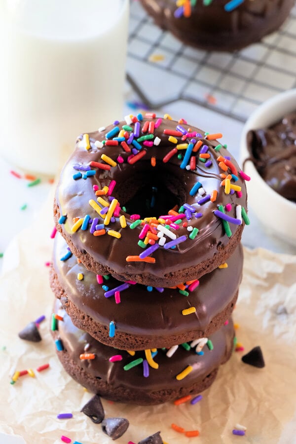 three chocolate donuts with sprinkles stacked