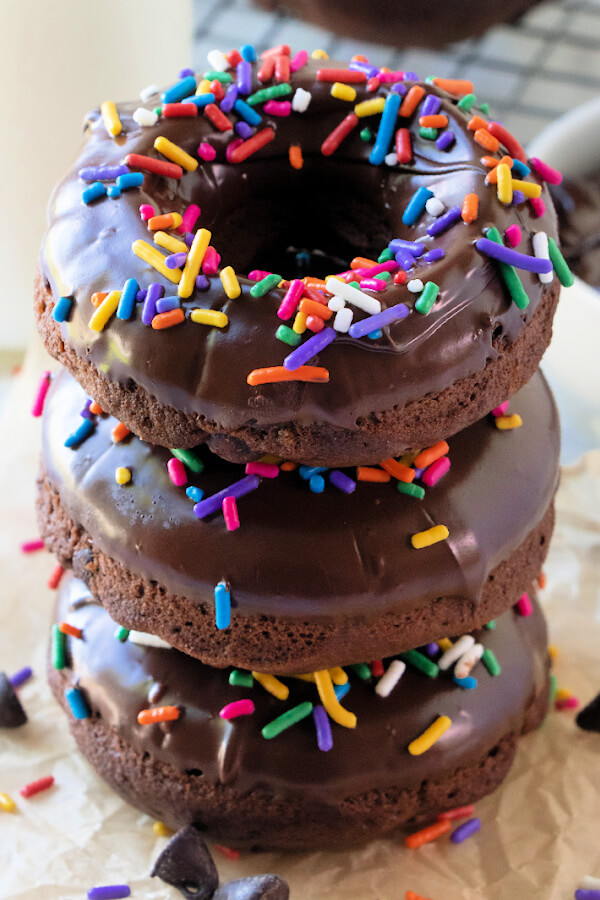 three chocolate donuts with sprinkles stacked