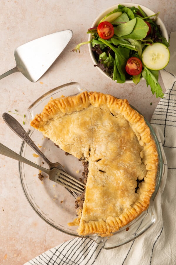 looking down onto pie with a couple of slices missing and utensils in pie plate