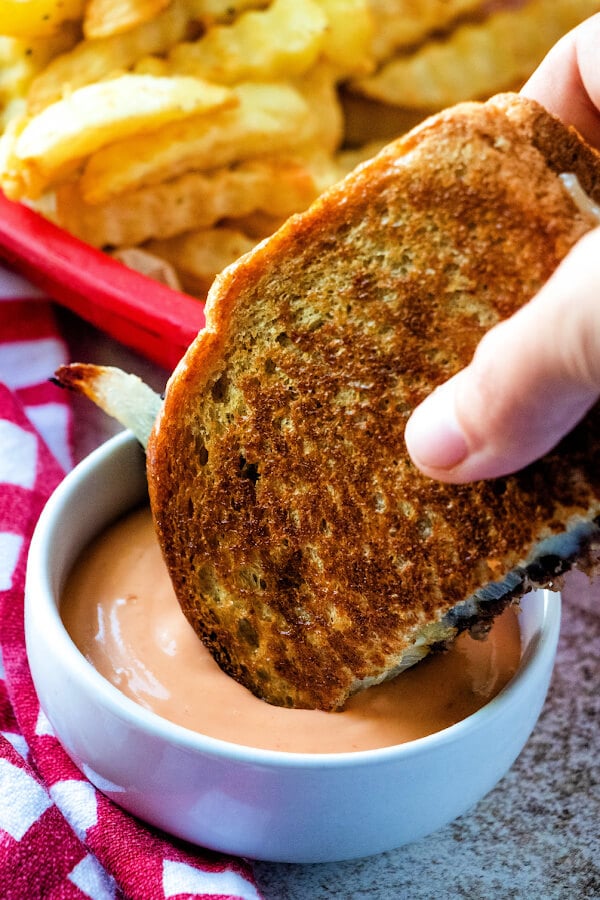 dunking patty melt sandwich into sauce