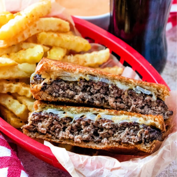 patty melt cut in half in red basket with fries