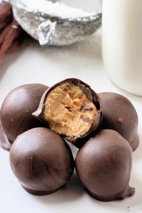 peanut butter balls stacked on board, one wiht a bite taken out of it