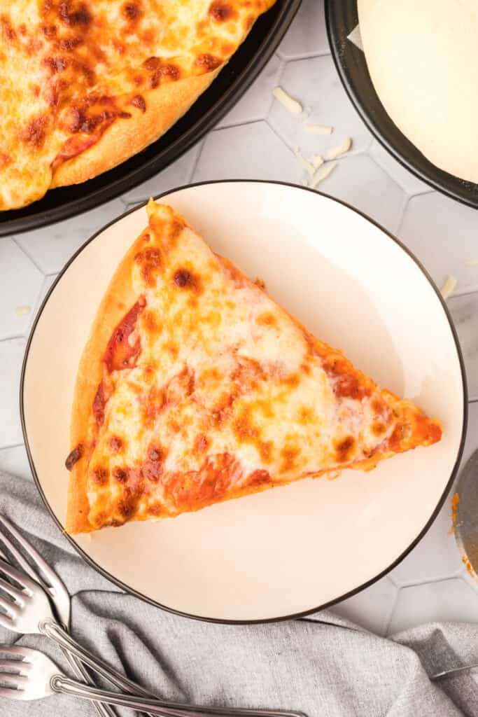 Slice of homemade cheese pizza on a plate made with soft and chewy Bread Machine Pizza Dough