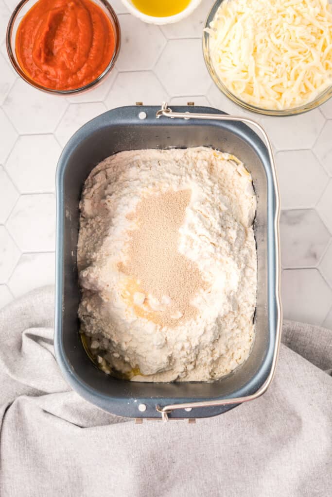 Ingredients layered in a bread machine pan for homemade Bread Machine Pizza Dough before starting the dough cycle