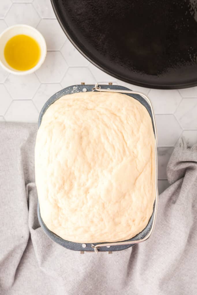 Risen Bread Machine Pizza Dough inside the bread machine pan after the dough cycle is complete