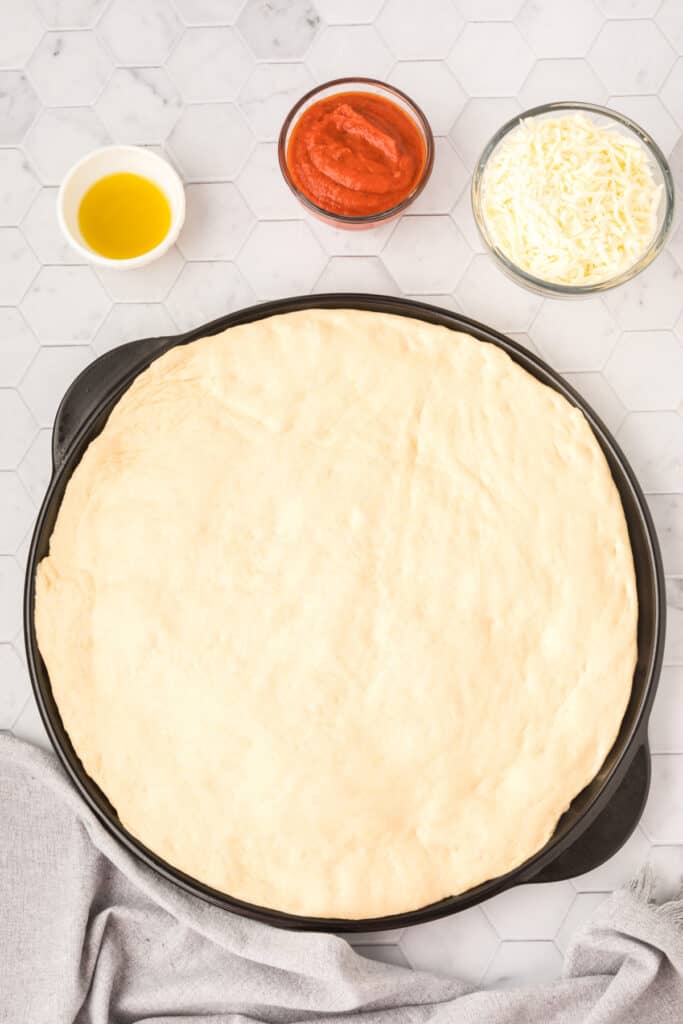 Homemade pizza dough pressed into a round pizza pan before prebaking