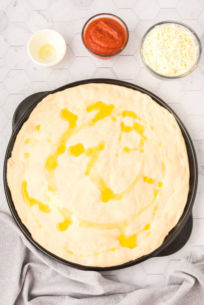 Olive oil drizzled over homemade pizza crust before baking for a golden chewy crust