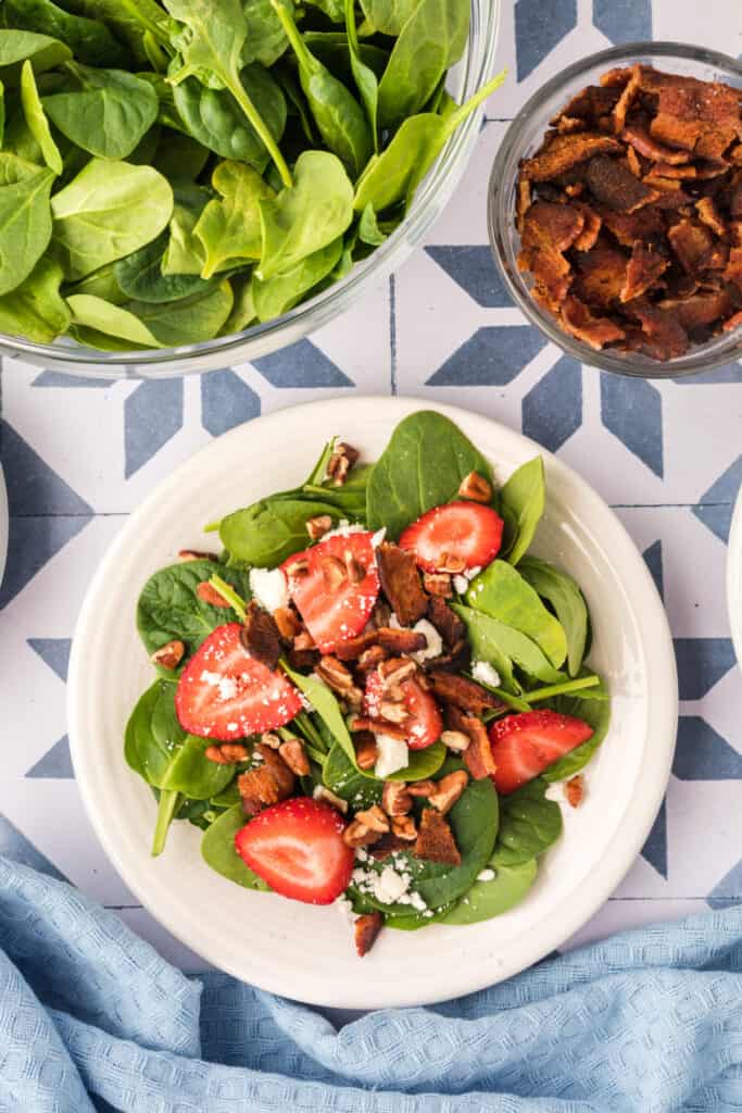 spinach, strawberries, feta, and bacon topped with chopped pecans for strawberry spinach salad