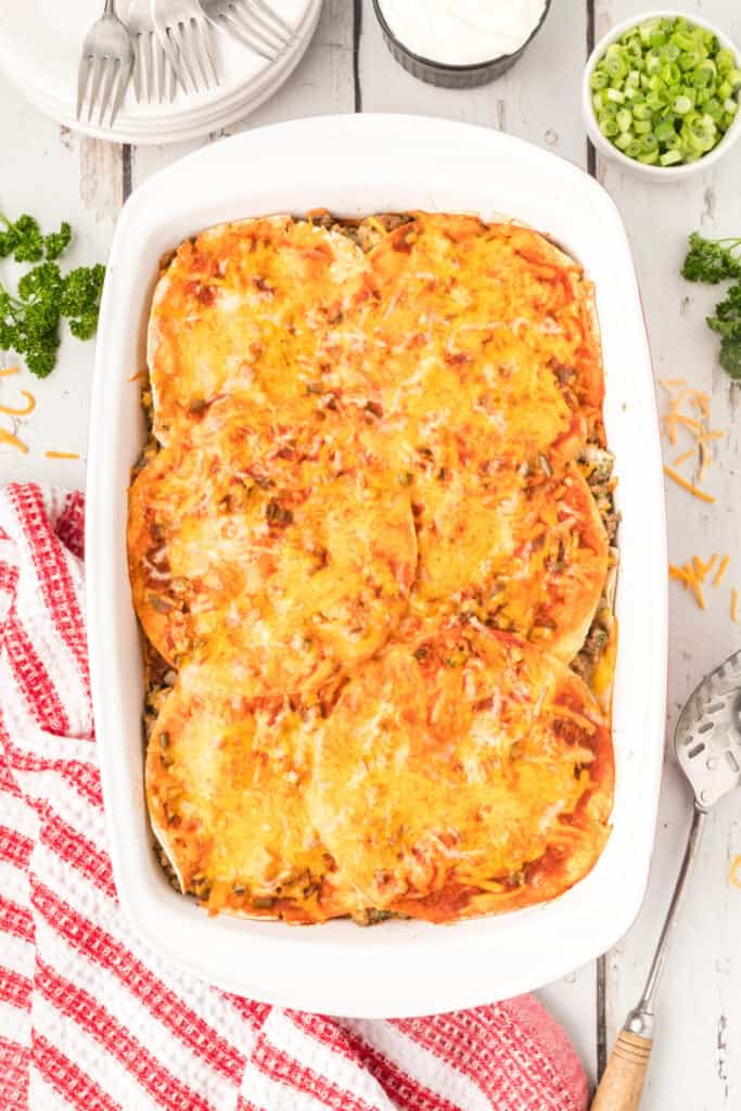 baked enchilada casserole with melted cheese in a white baking dish