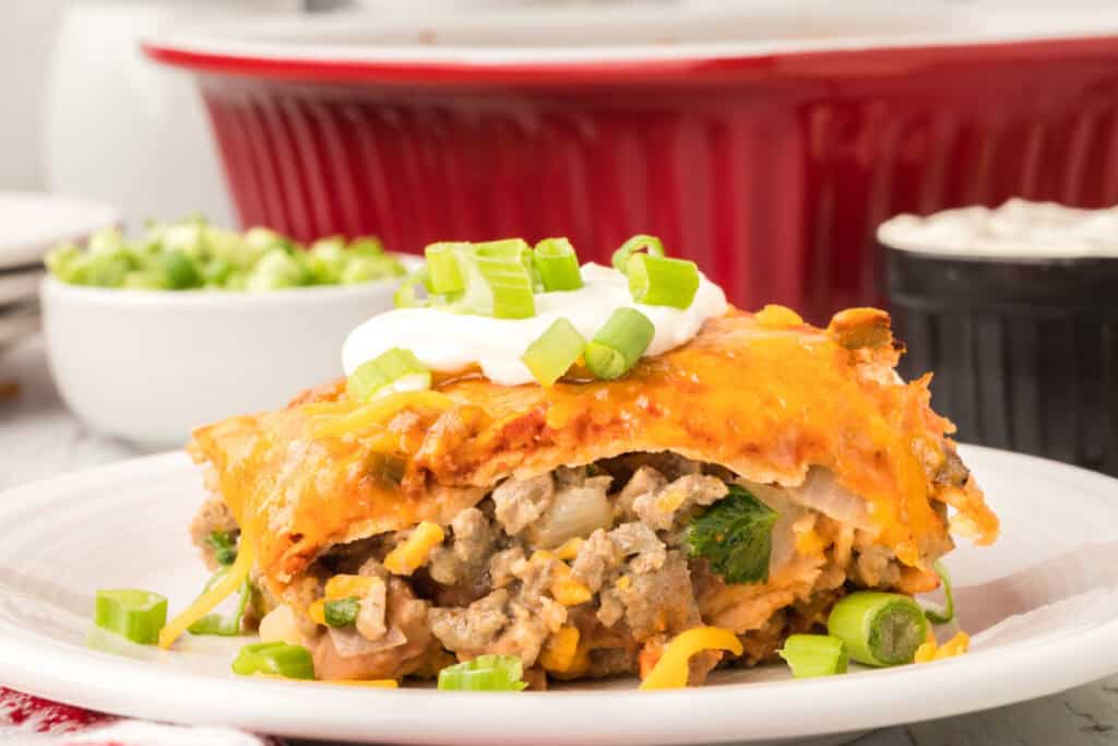 close up side view of enchilada casserole slice showing layers of beef, beans, and tortillas