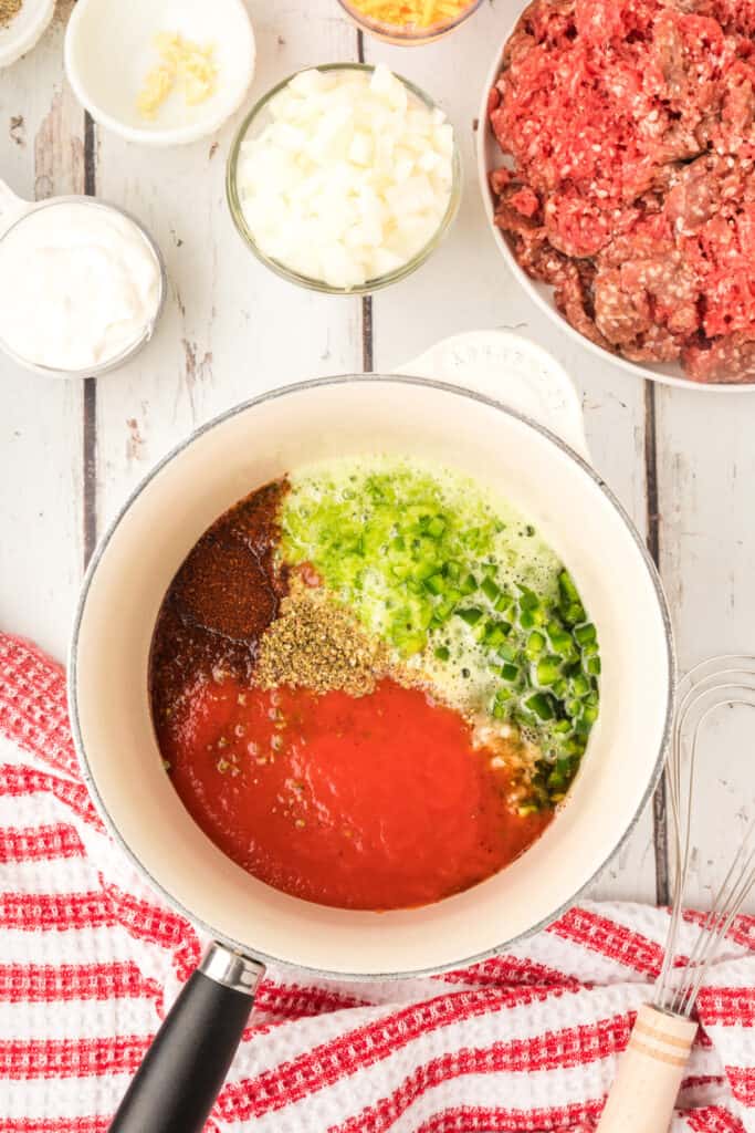 enchilada sauce ingredients combined in a saucepan before cooking with spices and vegetables visible