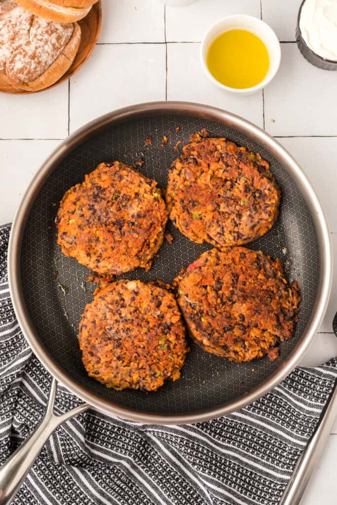 cooked Black Bean Nacho Burger patties in a skillet with browned edges