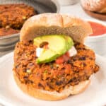 square image of Black Bean Nacho Burger on a bun with avocado, sour cream, and salsa