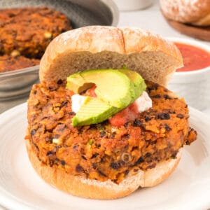 square image of Black Bean Nacho Burger on a bun with avocado, sour cream, and salsa
