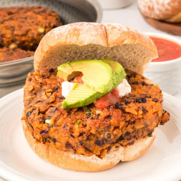 square image of Black Bean Nacho Burger on a bun with avocado, sour cream, and salsa